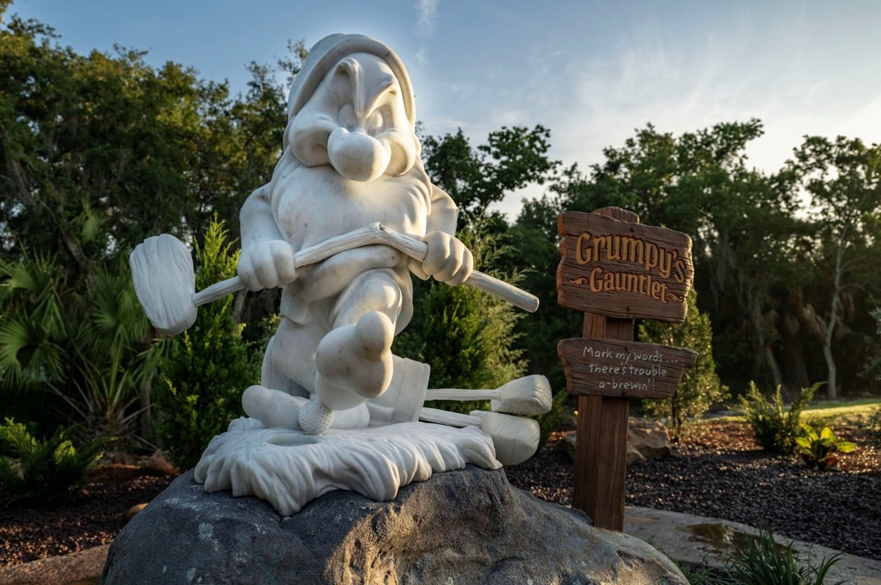 Marble statue of Grumpy beside the Grumpy's Gauntlet sign at Disney's Magnolia Golf Course
