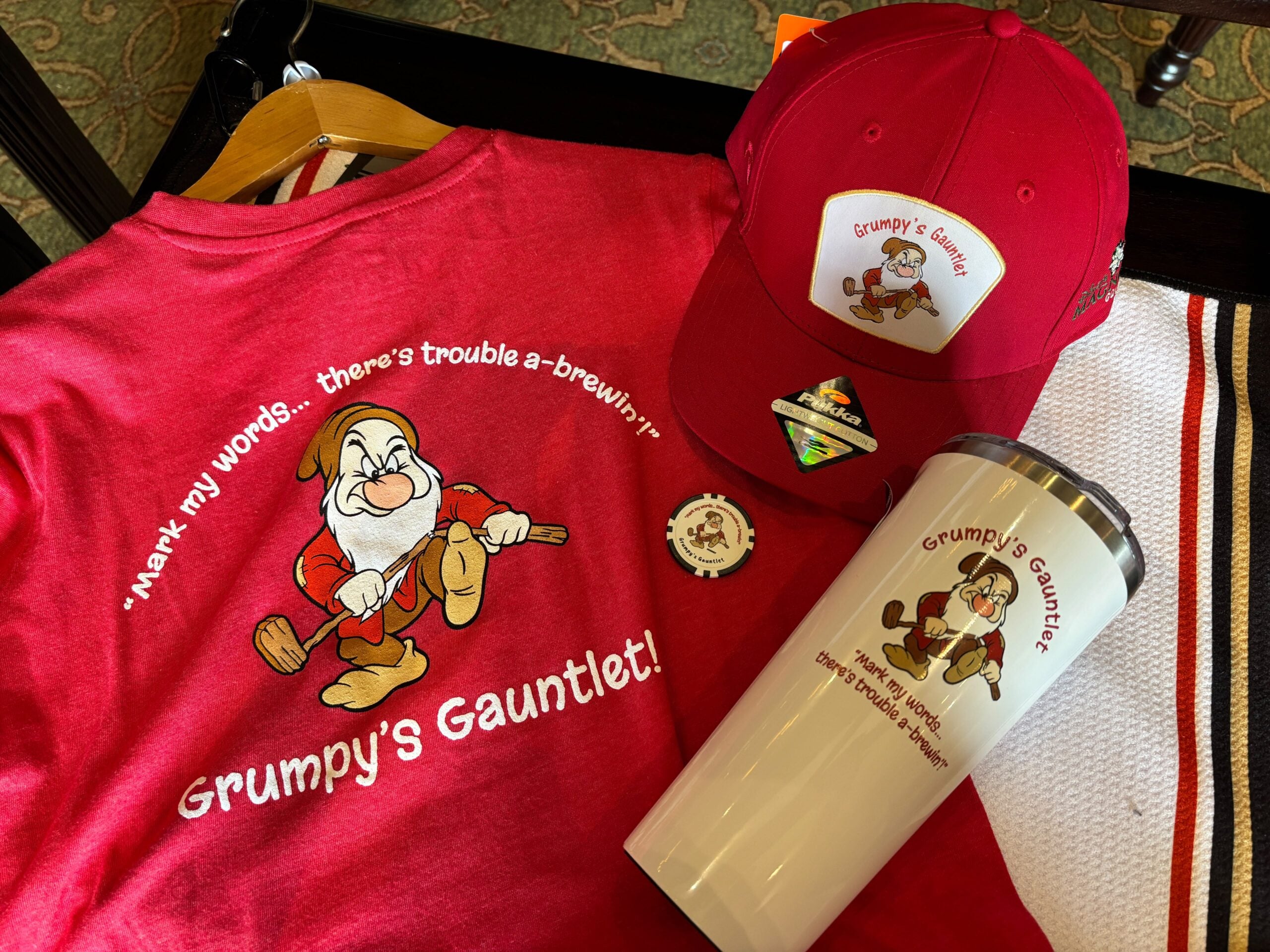 Grumpy's Gauntlet T-shirt, Pukka hat, poker-chip ball marker and Corkcicle tumbler laid out together